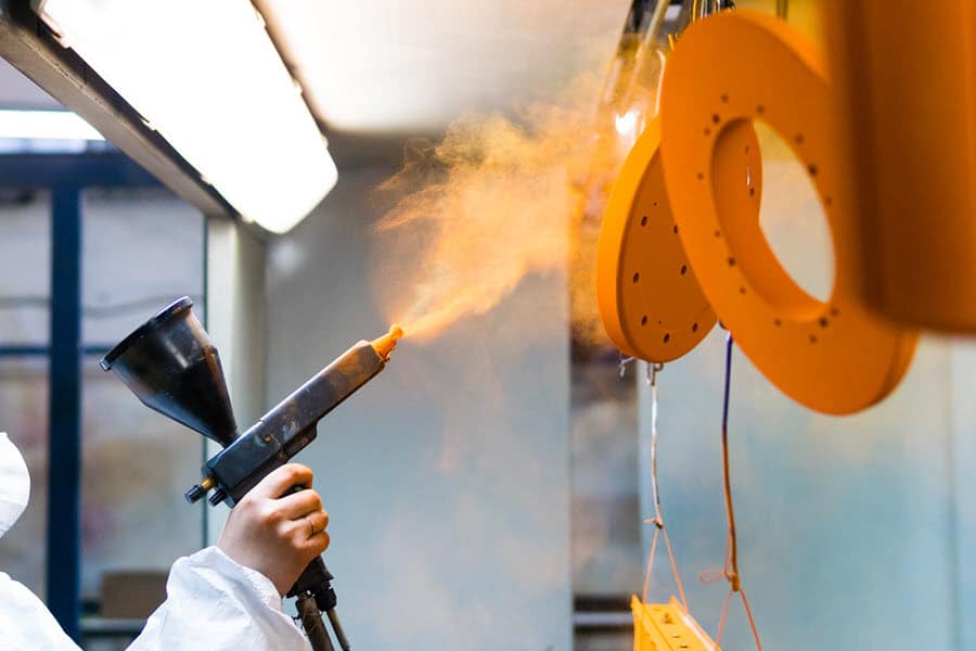 Worker using thermal spraying to coat metal.